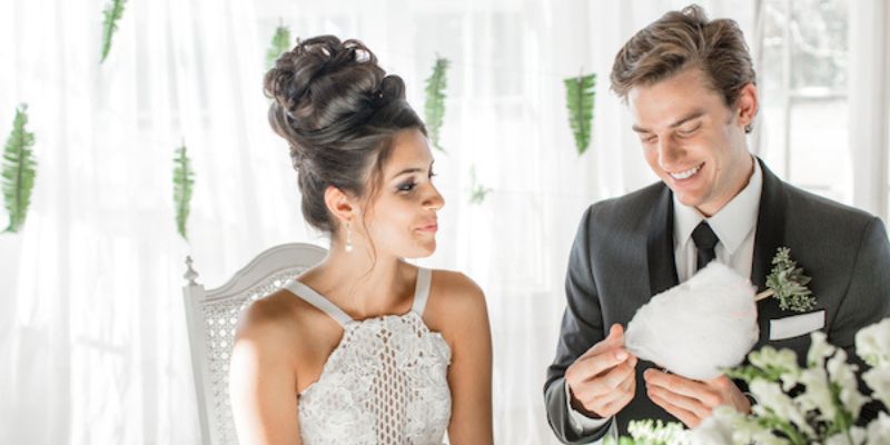 A couple wearing wedding attire reading an envelope