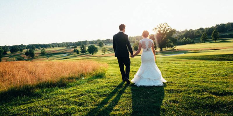 A newlywed couple gazing at the sunset in a field