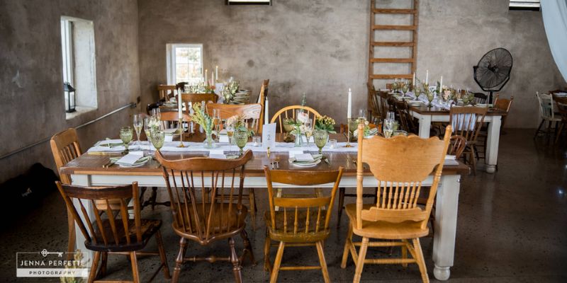 A detail shot showing a rustic table set with candles and white florals