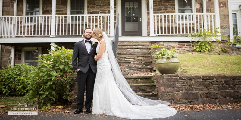 A newlywed couple posing in front of a house ksising