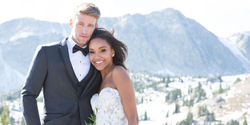 A couple wearing formalwear leaning on each other smiling