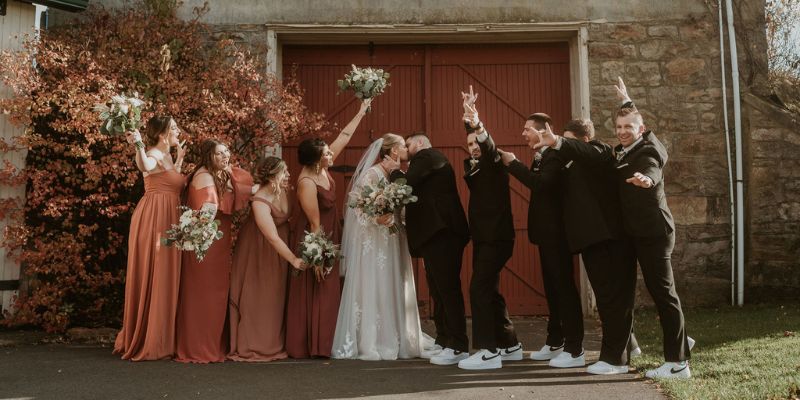 A wedding party cheering on a couple as they kiss