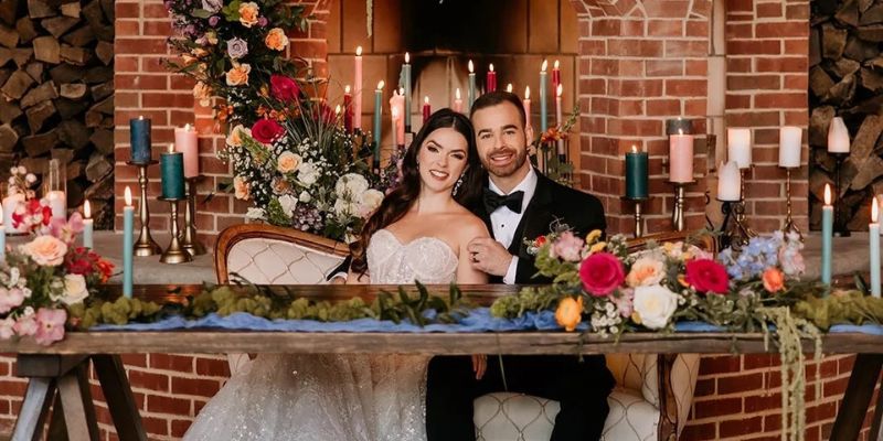 A picture of a couple wearing formalwear sitting in a well decorated table