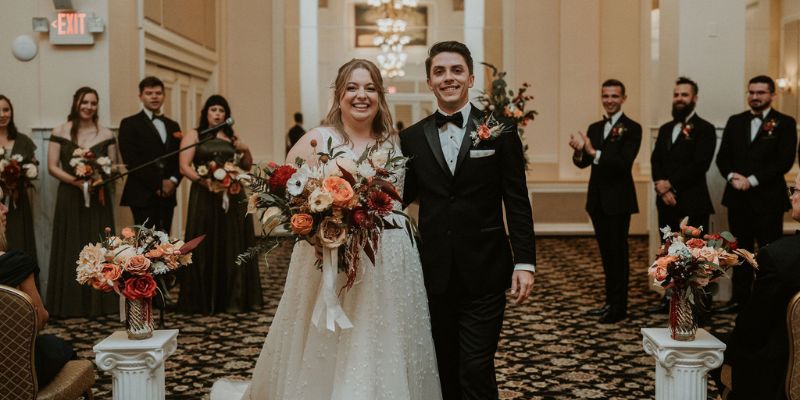 A bride and groom walking down the aisle smiling