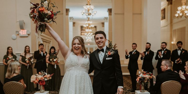 A bride and groom walking down the aisle smiling