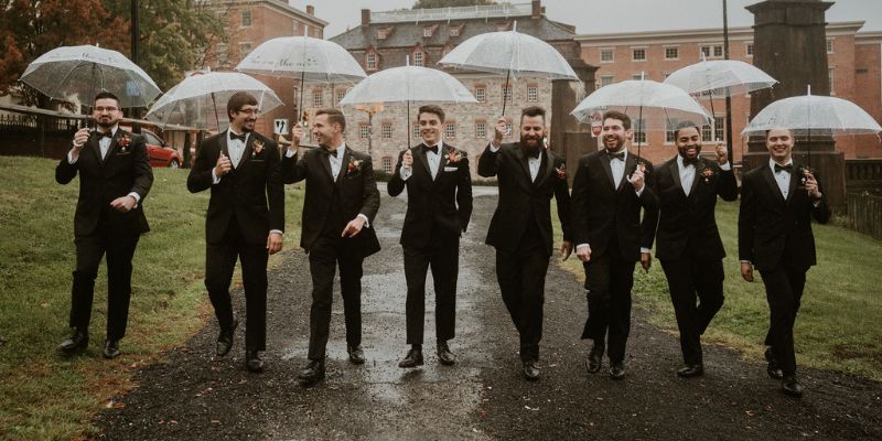 A bridal party posing with umbrellas outside