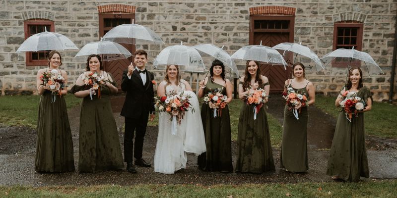 A bridal party posing with umbrellas outside