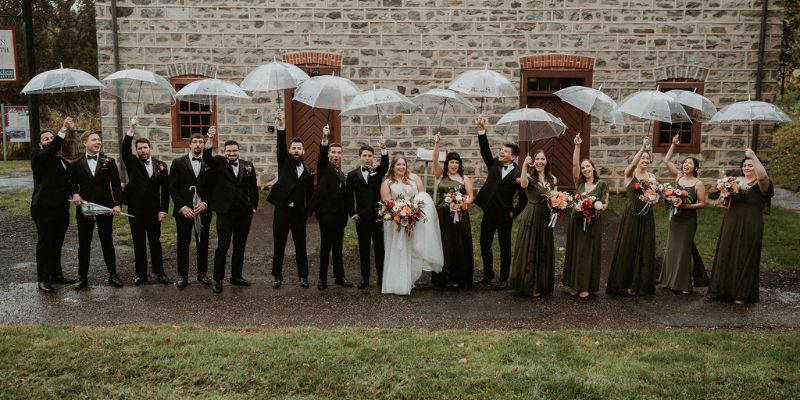 A bridal party posing with umbrellas outside