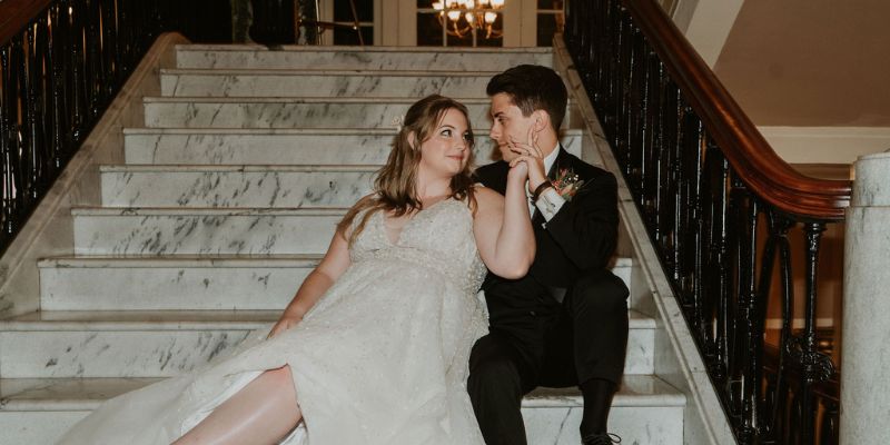 A newlywed couple posing on marble stairs